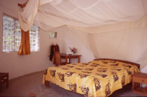 Bedroom with mosquito netting in Boukarou